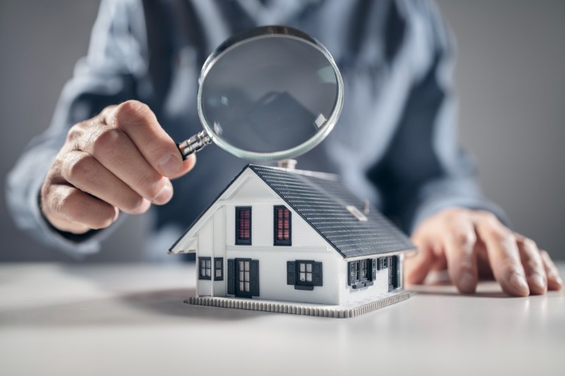House model with man holding magnifying glass