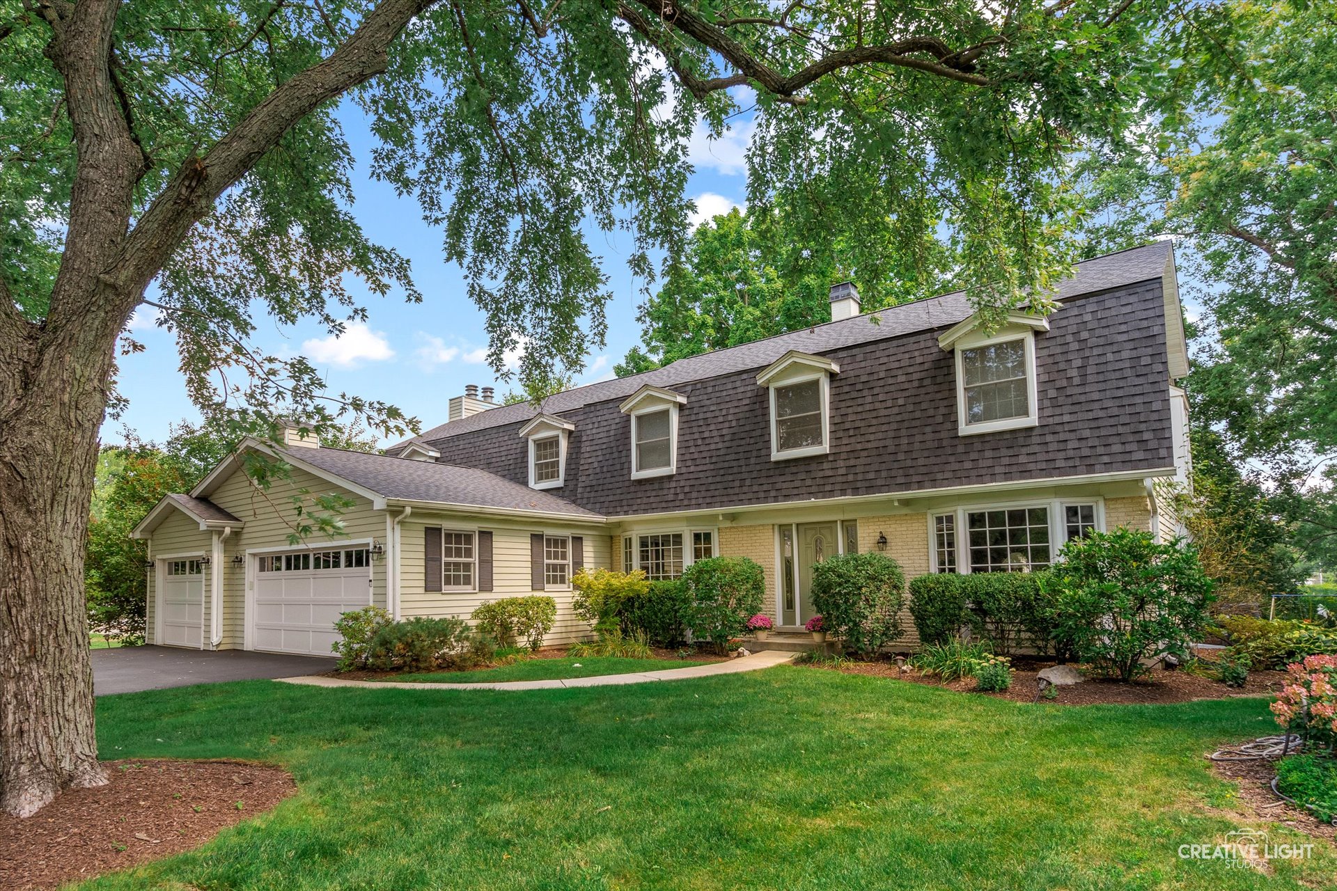 Front exterior of 1101 Barberry Court in Downers Grove with manicured landscaping, mature trees, and a classic two-story design with a shingled roof and attached two-car garage.
