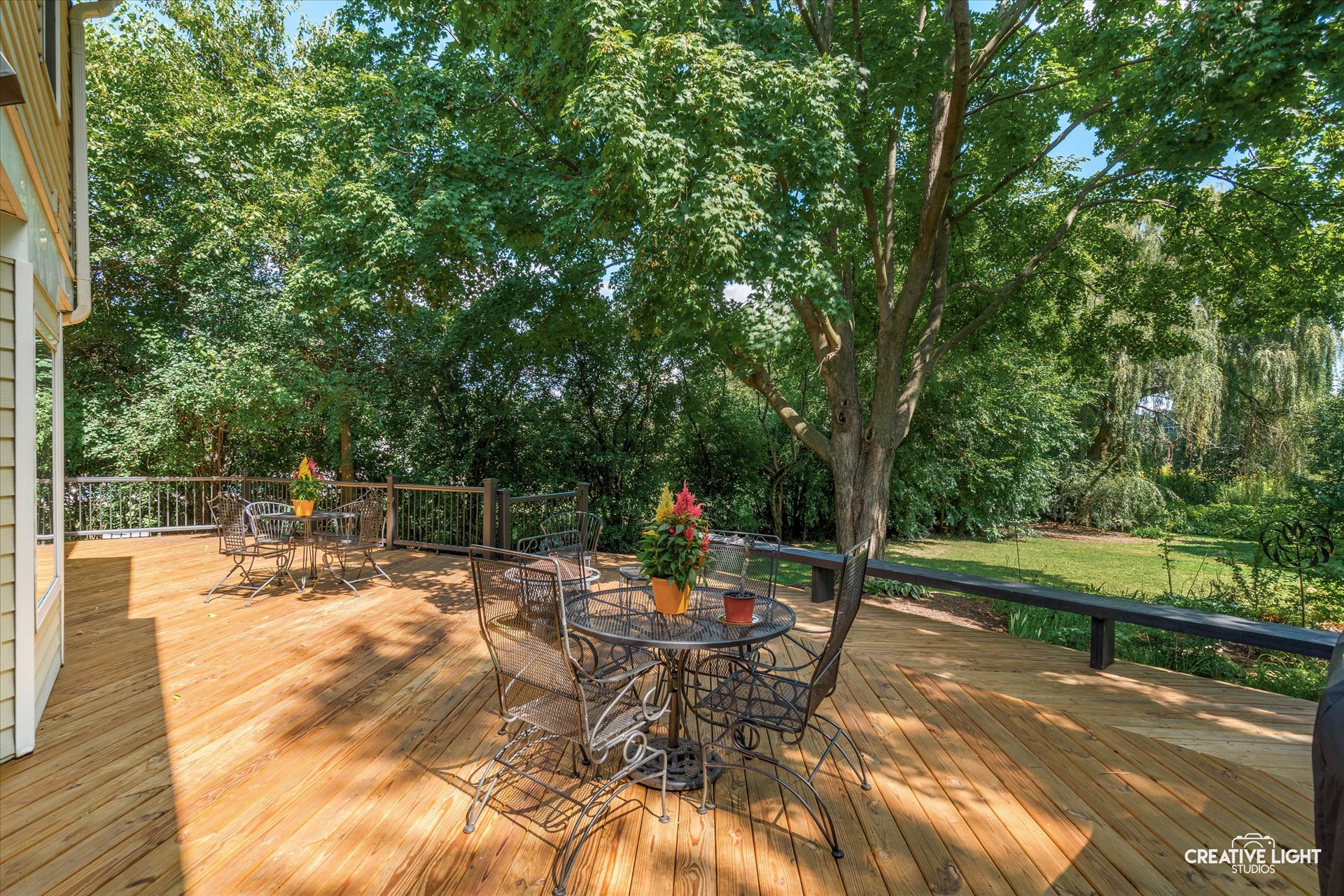 Back deck at 1101 Barberry Court Downers Grove with outdoor dining area surrounded by mature trees and lush landscaping.