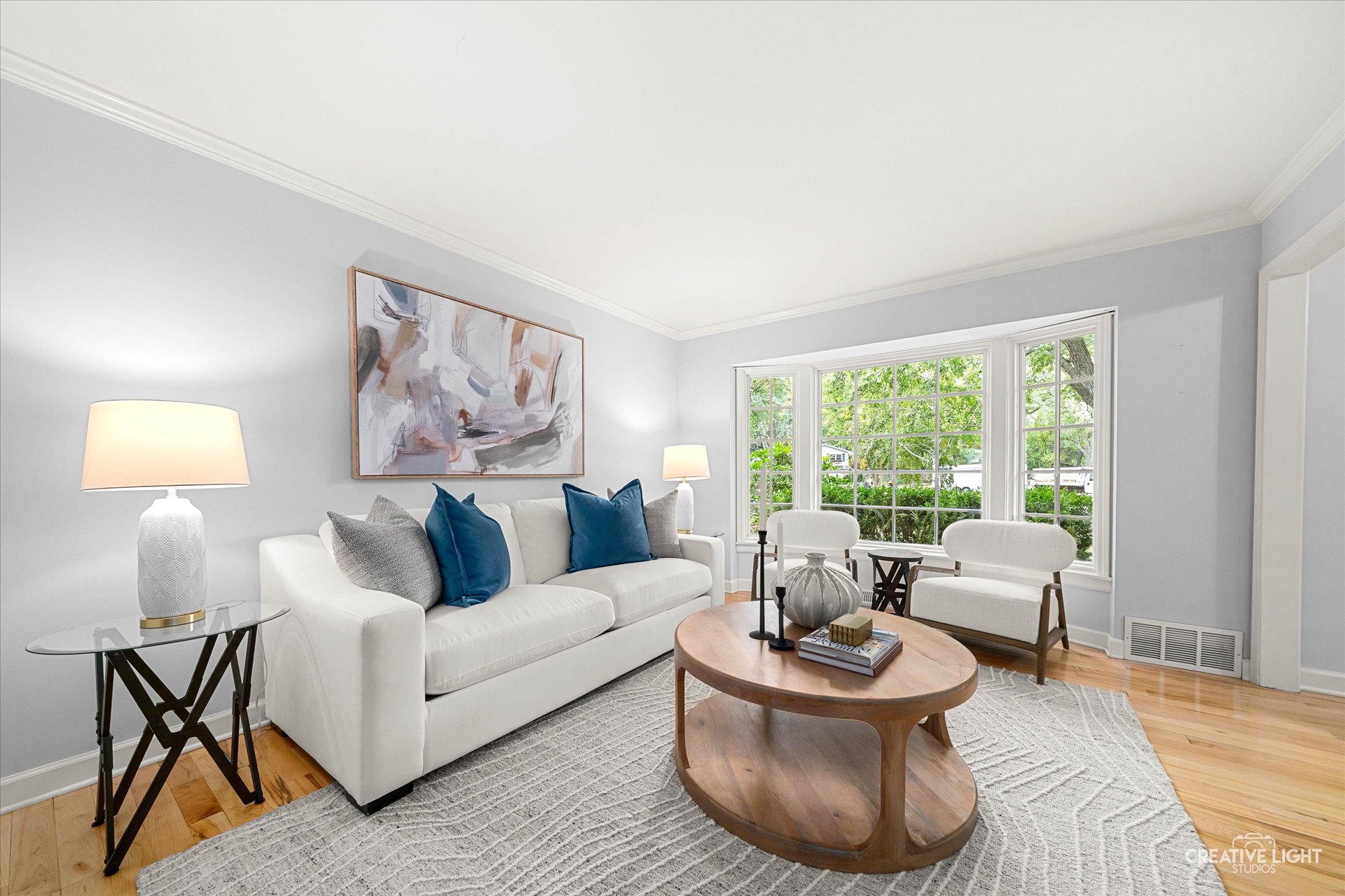 Living room at 1101 Barberry Court Downers Grove with light gray walls, large bay window, white sofa, and modern artwork above the sofa.