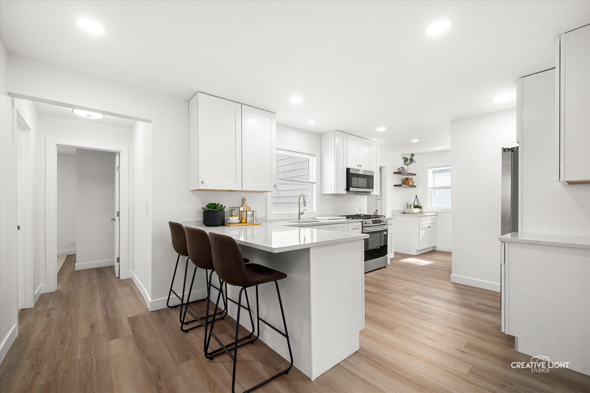 All-new white shaker kitchen with quartz counters, peninsula seating, open shelving, and stainless Frigidaire appliances at 5505 Pershing Ave